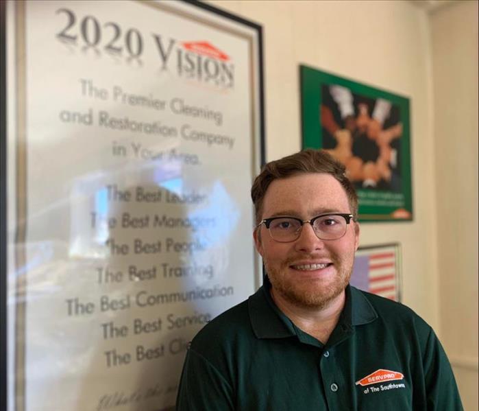 Red headed male in green SERVPRO polo in front of 2020 vision poster.