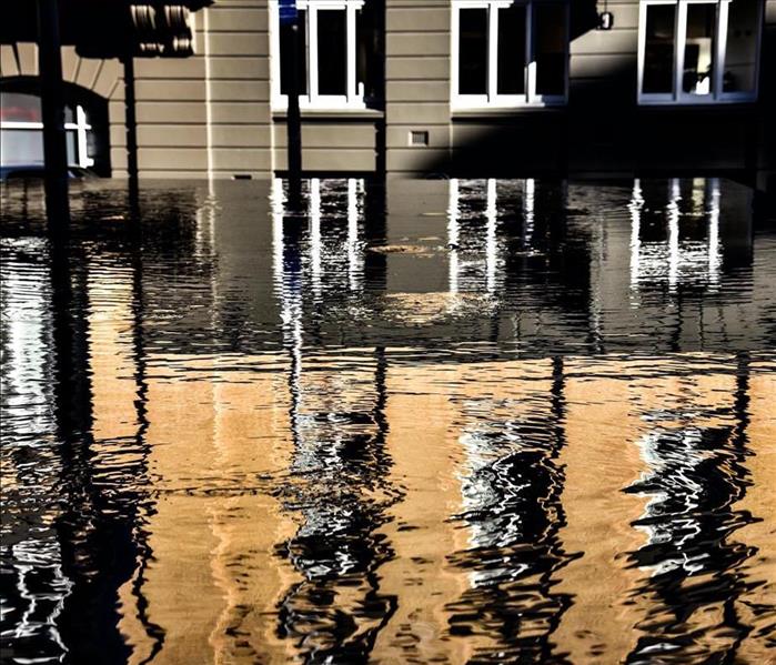 Exterior shot of high flood waters in a city street reflecting a nearby building.