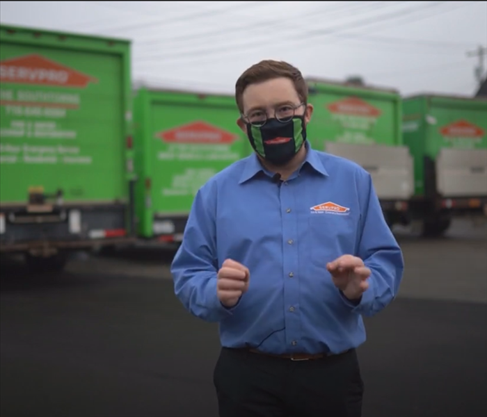 Dan from SERVPRO standing in front of a fleet of green trucks.